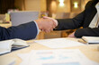 © DragonImages - Close-up image of senior entrepreneurs shaking hands after discussing reports with charts and diagrams