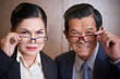 © DragonImages - Portrait of skeptical senior businessman and businesswoman taking off glasses and looking at camera