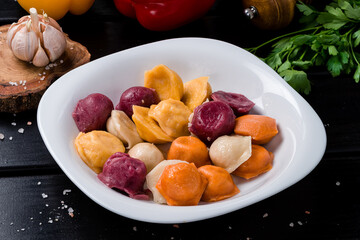 Sticker - boiled dumplings assorted, different colors ravioli on wooden table