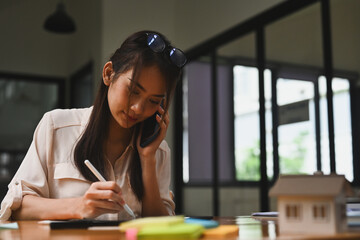 Portrait with Businesswoman talking on smartphone and using tablet on office desk, Mortgage loan approval home loan and insurance concept.