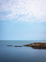 Wall Mural - Peaceful seascape over the glacial rock peninsula under bright white clouds 