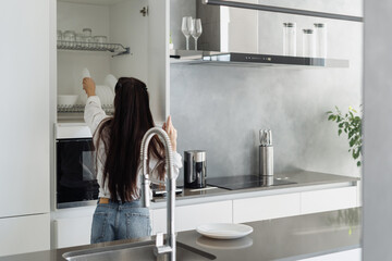 Wall Mural - Woman putting white plate into spacious storage drawer