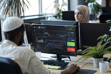 Sticker - African Muslim businessman sitting in front of computer monitor in working environment