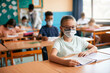 © Drazen - Schoolgirl wearing face mask while having class at school during COVID-19 pandemic.