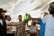 © pressmaster - Happy multiracial young people toasting with bottles of beer at rooftop party