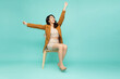 Attractive beautiful Asian businesswoman sitting on white modern chair and hands up raised arms from happiness, Excited businesswoman winner success concept