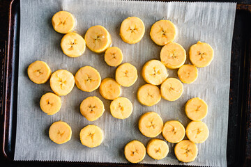 Wall Mural - Sliced Plantains on a Parchment Covered Sheet Pan: Slices of raw cooking bananas on a baking sheet