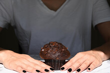 Chocolate muffin between white woman's hands