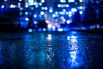 Wall Mural - Rainy night in the big city, alley with cars on the background of glowing windows of the house opposite. View from the level of asphalt