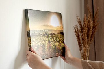 canvas print with gallery wrap and dry grass interior decor. woman hangs landscape photography on wh