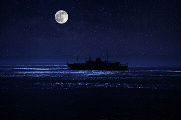 Wall Mural - Beautiful night scene at sea. Dramatic moon over sea at night with silhouette of the ship. Selective focus