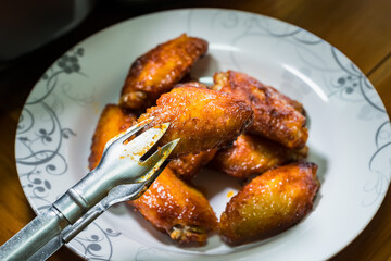 Wall Mural - Dish of grilled chicken wings over wooden table background.