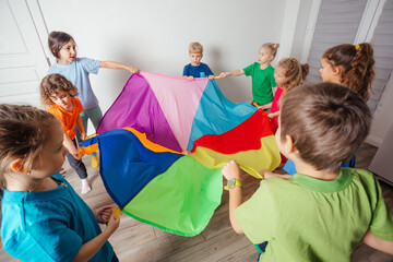 Canvas Print - Children stretching colorful parachute for fun team games