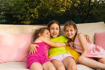 Wall Mural - Cheerful sister laying on porch swing, embracing