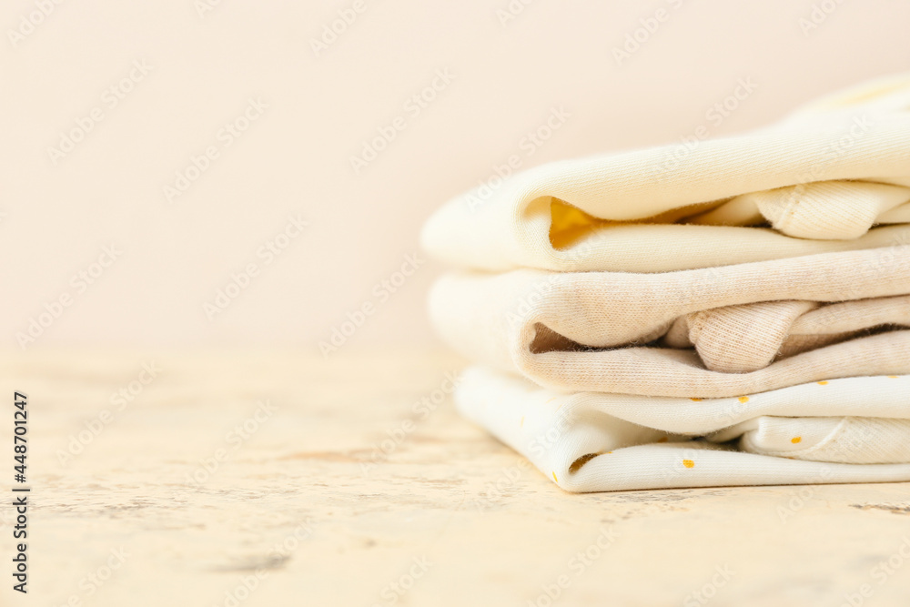 Stack of baby clothes on color background