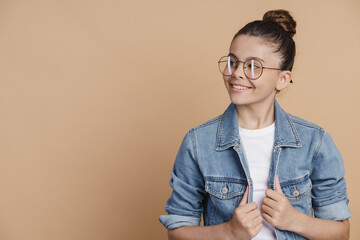 Wall Mural - Cute, attractive teenage girl with hair pulled up in glasses posing on a brown background. Place for text, copy space