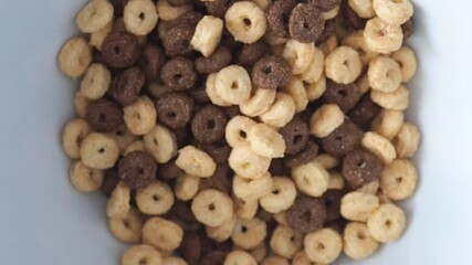 Wall Mural - Dry breakfast cereals are poured into a white bowl, chocolate and corn flakes, a healthy meal.