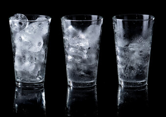 Wall Mural - Melting ice in clear glass isolated on black