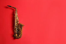 Beautiful Saxophone On Red Background, Top View. Space For Text