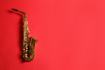 Beautiful saxophone on red background, top view. Space for text