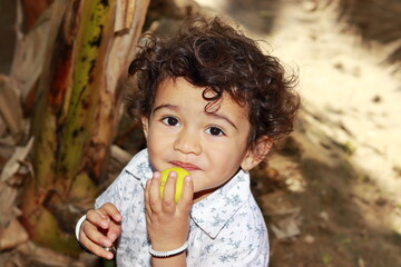 Close-up portrait of An Asian little male boy eating ripe fruit in the garden