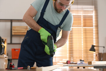 Sticker - Carpenter working with electric drill at table indoors