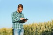 © Serhii - Happy mature technician checking the growth of the wheat for a quality control in a cereal field in summer