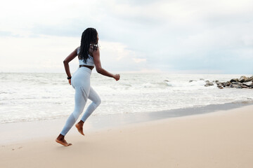 Wall Mural - Young woman enjoying running on beach in the morning on summer day