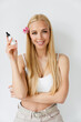 © Drobot Dean - Young blonde woman with flower smiling while showing face serum