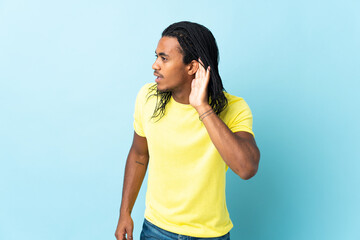 Wall Mural - Delivery African American man with braids isolated on white background listening to something by putting hand on the ear