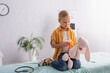 © LIGHTFIELD STUDIOS - Girl holding pills near soft toy and stethoscope on medical couch