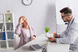 © LIGHTFIELD STUDIOS - doctor writing diagnosis while looking at woman holding head near forehead during consultation