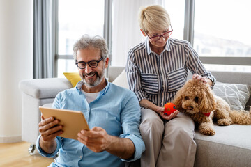 Wall Mural - Beautiful happy mature couple is using a digital tablet, talking and smiling at home