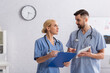 © LIGHTFIELD STUDIOS - doctors with clipboard and digital tablet looking at each other while talking in clinic