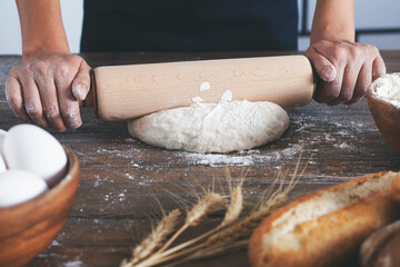 Woman preparing bread dough on wooden table in a bakery close up