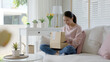 © ChayTee - Young happy asia people teen girl smile enjoy unbox post mail sit relax at home comfort sofa couch feel joy amazed awe wow in omni channel fast send parcel via online sale shop store e-commerce order.