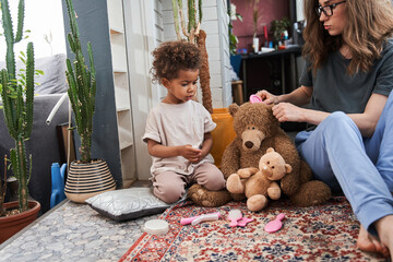 Wall Mural - Woman is sitting at the floor near her nice little daughter and playing