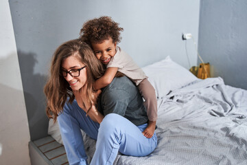 Wall Mural - Girl embracing her lovely mother while enjoying of the morning with her