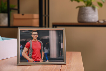 Sticker - Framed photo of happy young man on wooden table in room. Space for text