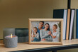 © New Africa - Framed family photo on wooden shelf indoors