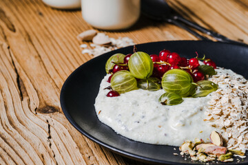 Wall Mural - Breakfast smoothie bowl with gooseberries, red currants, rolled oats, pistachios