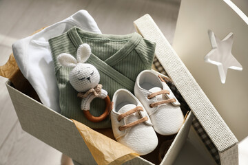 Wall Mural - Box with baby clothes, shoes and toy on chair indoors