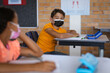 © WavebreakMediaMicro - Caucasian boy wearing face mask sitting on his desk in the class at elementary school