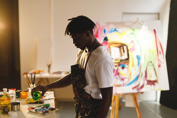 Wall Mural - African american male painter at work holding paint in art studio