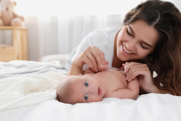 Wall Mural - Happy young mother with her cute baby on bed at home