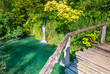 Wooden footpath at Plitvice national park, Croatia. Pathway in the forest near the lake and waterfall. Fresh beautiful nature, peaceful place. Famous tourist destination.