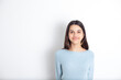 © Анна Брусницына - Portrait of a smiling teenage girl with dark hair and brown eyes. White background. blue blouse. Place for text