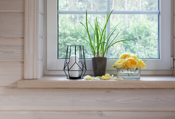 Yellow roses on windowsill, candles, autumn leaves, lantern.