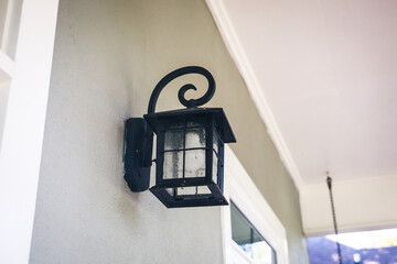 Retro black metal iron outdoor light lamp lantern hung on the exterior front entrance of a house home