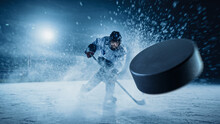 Ice Hockey Rink Arena: Professional Player Shooting The Puck With Hockey Stick. Focus On 3D Flying Puck With Blur Motion Effect. Dramatic Wide Shot, Cinematic Lighting.